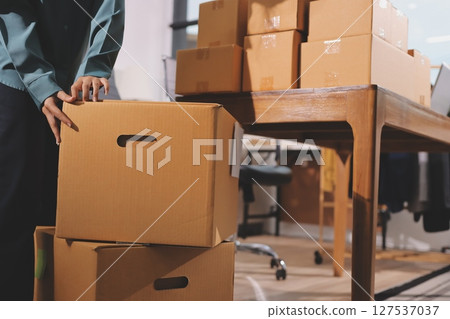 Startup SME small business entrepreneur of freelance Asian woman wearing apron using laptop and box to receive and review orders online to prepare to pack sell to customers, online sme business ideas. 127537037