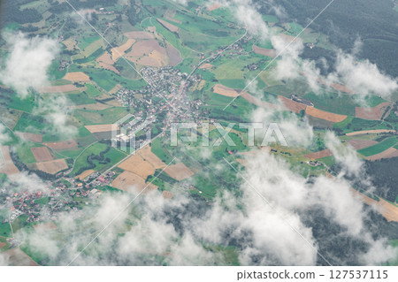 Aerial view of a tranquil countryside village beneath the vast expanse of clouds Aerial view of a tranquil countryside village beneath the vast expanse of clouds 127537115