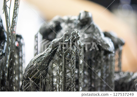 An object printed on a 3D printer from hardened rubber close-up. Model black color created on a 3D printer from hardened rubber under influence of ultraviolet light. SLA 3D printing. Stereolithography 127537249