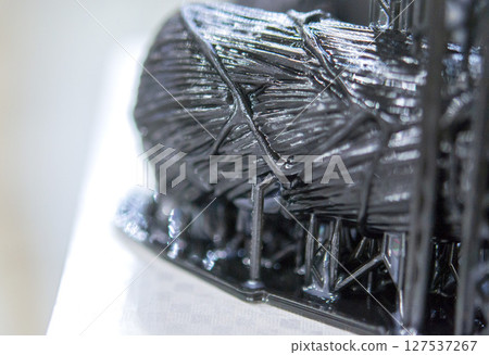 An object printed on a 3D printer from hardened rubber close-up. Model black color created on a 3D printer from hardened rubber under influence of ultraviolet light. SLA 3D printing. Stereolithography An object printed on a 3D printer from hardened rubber close-up. Model black color created on a 3D printer from hardened rubber under influence of ultraviolet light. SLA 3D printing. Stereolithography 127537267