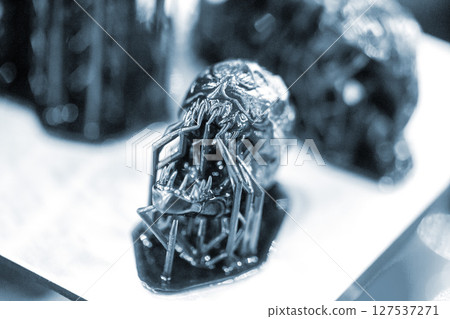 An object printed on a 3D printer from hardened rubber close-up. Model black color created on a 3D printer from hardened rubber under influence of ultraviolet light. SLA 3D printing. Stereolithography 127537271