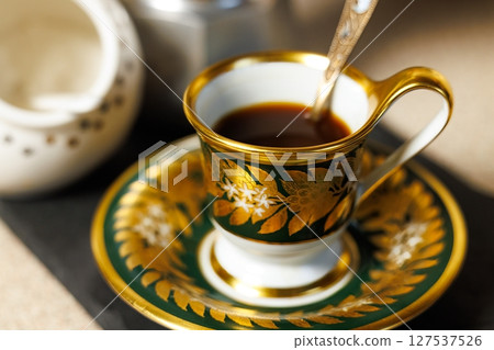 Elegant coffee cup with intricate design sitting on a stylish plate, capturing the warmth of a cozy afternoon Elegant coffee cup with intricate design sitting on a stylish plate, capturing the warmth of a cozy afternoon 127537526