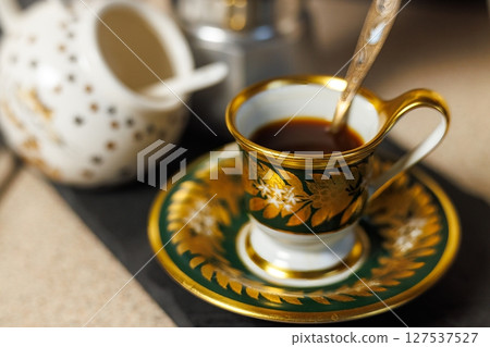 Elegant coffee setup with ornate cup and pot during a quiet afternoon at home 127537527