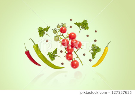 Flying tomatoes, parsley, hot pepper and black pepper on a green background. Set for salad preparation, healthy snacks. Design element for product label Flying tomatoes, parsley, hot pepper and black pepper on a green background. Set for salad preparation, healthy snacks. Design element for product label 127537635