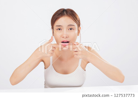 Acne removal scene where a woman squeezes acne gently, dealing with forehead blemishes, skin problems, and the reality of blackheads in a personal beauty routine. isolated studio white background 127537773