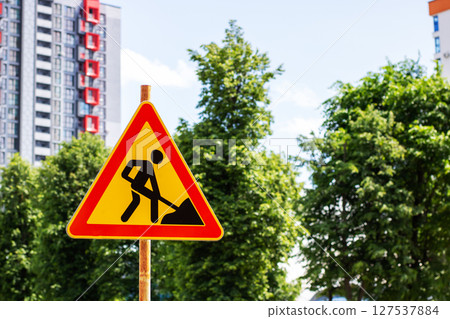 A yellow and red construction sign featuring a man on it for safety A yellow and red construction sign featuring a man on it for safety 127537884