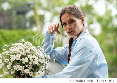 Daisies Woman Portrait: Girl with flowers poses outdoors on the daytime for springtime photoshoot. Daisies Woman Portrait: Girl with flowers poses outdoors on the daytime for springtime photoshoot. 127538304