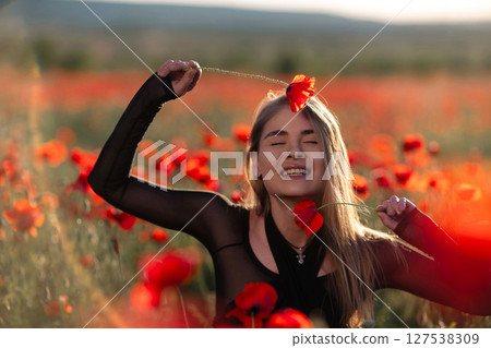 Poppy field woman summer: Girl with poppies enjoys nature's beauty in vibrant poppy field during summer. Poppy field woman summer: Girl with poppies enjoys nature's beauty in vibrant poppy field during summer. 127538309