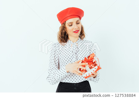 Woman wearing a red hat and a white polka dot shirt is holding a red present Woman wearing a red hat and a white polka dot shirt is holding a red present 127538884