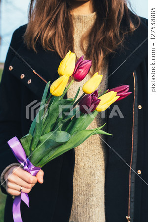 Woman is holding a bouquet of tulips in her hand 127538885