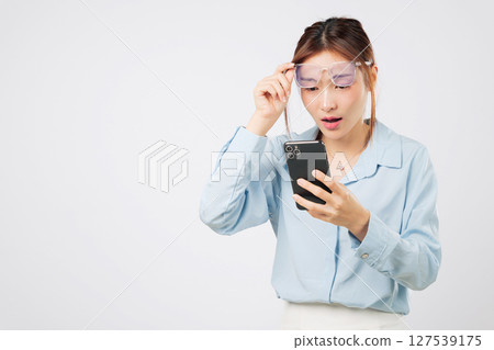 Vision loss and problem blurred with screen reading, woman holding glasses, vision affected by age, looking at mobile phone with blurry sight and bad focus. isolated studio white background 127539175