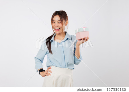 Gift brings happiness to excited woman as she holds pink ribbon box on side palm with smile, posing for a portrait with her special gift box on a joyful day. isolated studio white background Gift brings happiness to excited woman as she holds pink ribbon box on side palm with smile, posing for a portrait with her special gift box on a joyful day. isolated studio white background 127539180