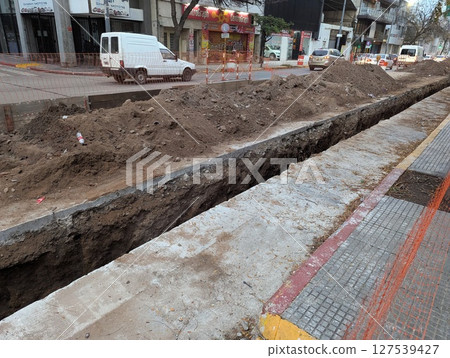 Cordoba, Argentina - May 08, 2025: Construction work. Laying underground utilities in the city center. Trench and soil dumps for laying utilities. 127539427