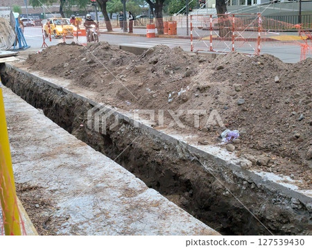 Cordoba, Argentina - May 08, 2025: Construction work. Laying underground utilities in city center. Trench and soil dumps for the laying utilities. Cordoba, Argentina - May 08, 2025: Construction work. Laying underground utilities in city center. Trench and soil dumps for the laying utilities. 127539430