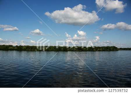 Panoramic view of the Monastery Island on Dnieper River. Dnieper City. Ukraine. Reflection of the sky with clouds on the surface of the water. 127539732
