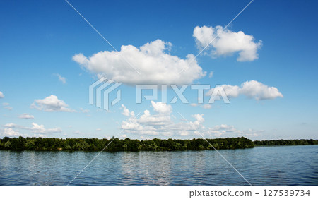 Panoramic view of the Monastery Island on the Dnieper River. Dnieper City. Ukraine. Reflection of sky with clouds on the surface of the water. 127539734