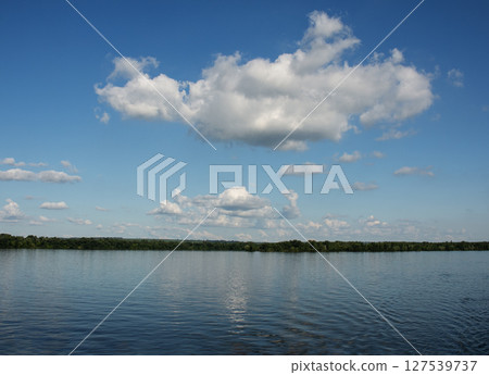 Panoramic view of Dnieper River bank. Reflection of the sky with clouds on the water surface. Panoramic view of Dnieper River bank. Reflection of the sky with clouds on the water surface. 127539737