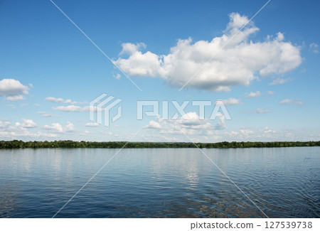 Panoramic view of the Dnieper River bank. Reflection of sky with clouds on the water surface. Panoramic view of the Dnieper River bank. Reflection of sky with clouds on the water surface. 127539738
