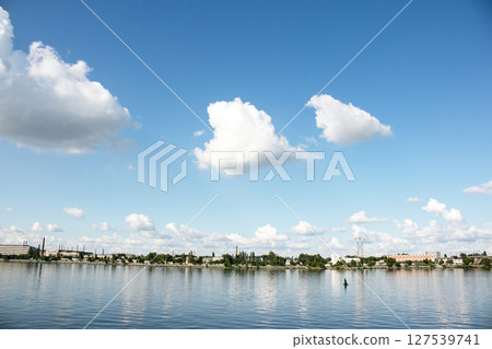 Panoramic view of left bank of the Dnieper River. Dnieper. Ukraine. Reflection of the sky with clouds on the water surface. Panoramic view of left bank of the Dnieper River. Dnieper. Ukraine. Reflection of the sky with clouds on the water surface. 127539741