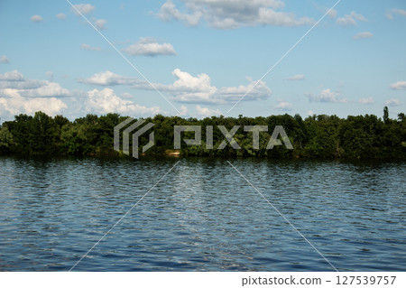 Panoramic view of the Monastery Island on the Dnieper River. Dnieper City. Ukraine. Reflection of the sky with clouds on the surface of the water. Panoramic view of the Monastery Island on the Dnieper River. Dnieper City. Ukraine. Reflection of the sky with clouds on the surface of the water. 127539757