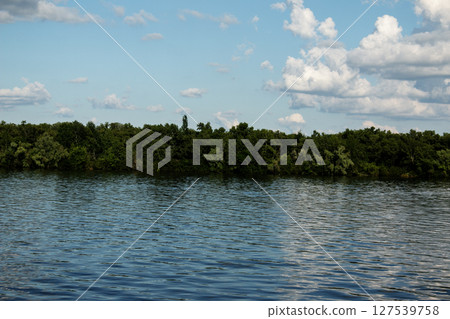 Panoramic view of Monastery Island on the Dnieper River. Dnieper City. Ukraine. Reflection of the sky with clouds on the surface of the water. Panoramic view of Monastery Island on the Dnieper River. Dnieper City. Ukraine. Reflection of the sky with clouds on the surface of the water. 127539758
