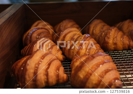 Golden flaky croissants on a crisp plate, its buttery layers and crescent shape capturing morning indulgence in perfect simplicity. Golden flaky croissants on a crisp plate, its buttery layers and crescent shape capturing morning indulgence in perfect simplicity. 127539816