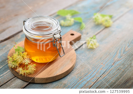 Linden honey in glass jar with wooden honey dipper Linden honey in glass jar with wooden honey dipper 127539995