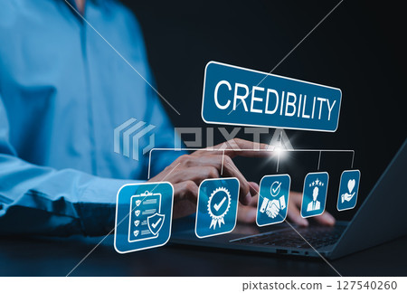 Credibility and trust in business concept. Businessman using laptop with icons credibility, trust, reputation, verification, integrity, reliable, authentic, commitment, regard, and quality assurance. Credibility and trust in business concept. Businessman using laptop with icons credibility, trust, reputation, verification, integrity, reliable, authentic, commitment, regard, and quality assurance. 127540260