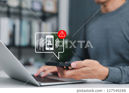 Phone scam alert notification concept. A man holding smartphone with scam warning notification, fraudulent calls, cybersecurity threats, fraud, scammer, and telecommunication security awareness. 127540266