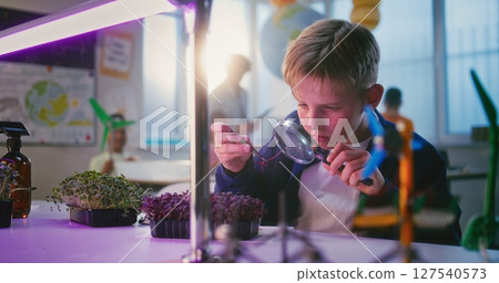 Elementary School Boy Sitting at the Table and Using Smartphone, Growing Experimental Microgreens Elementary School Boy Sitting at the Table and Using Smartphone, Growing Experimental Microgreens 127540573