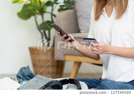 Happy young woman with credit card booking vacation at travel agency or making hotel reservation online 127540589