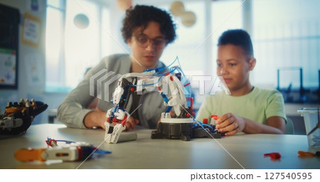 Elementary School Student Studying Model of Robotic Arm. Young Teacher Educating Boy 127540595