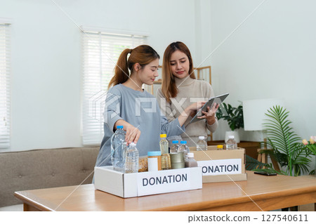 charity, donation and volunteering concept. Volunteer prepare foodstuff box containing food to donate to people poor, disaster victim at home 127540611
