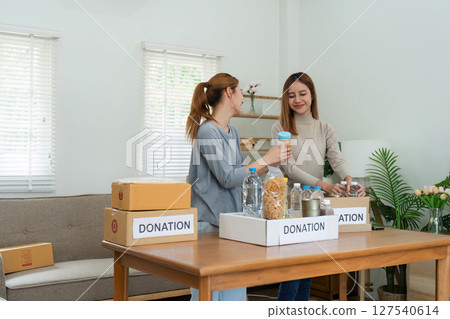 charity, donation and volunteering concept. Volunteer prepare foodstuff box containing food to donate to people poor, disaster victim at home 127540614