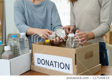 charity, donation and volunteering concept. Volunteer prepare foodstuff box containing food to donate to people poor, disaster victim at home 127540619