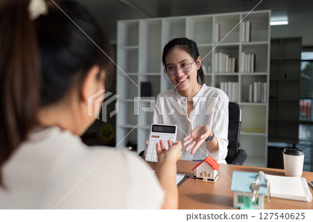 Real estate agent calculating the buyer's monthly payments. Customer discussing for the contract to buy home and insurance or loan real estate or property. 127540625