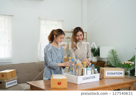 charity, donation and volunteering concept. Volunteer prepare foodstuff box containing food to donate to people poor, disaster victim at home 127540631