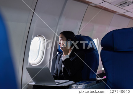 Beautiful Asian businesswoman working with laptop and mobile in aeroplane. working, travel, business concept Beautiful Asian businesswoman working with laptop and mobile in aeroplane. working, travel, business concept 127540640