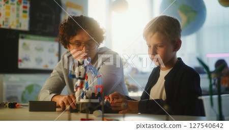 Elementary School Student Studying Model of Innovative Robotic Arm. Teacher Educating Smart Young Boy Elementary School Student Studying Model of Innovative Robotic Arm. Teacher Educating Smart Young Boy 127540642