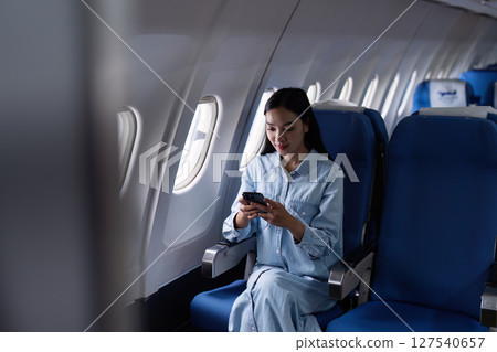 Asian people female person onboard, airplane window, using mobile while on the plane 127540657