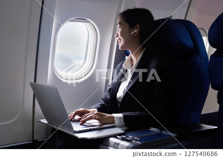 businesswoman flying and working in an airplane in first class, businesswoman sitting inside an airplane using laptop businesswoman flying and working in an airplane in first class, businesswoman sitting inside an airplane using laptop 127540686