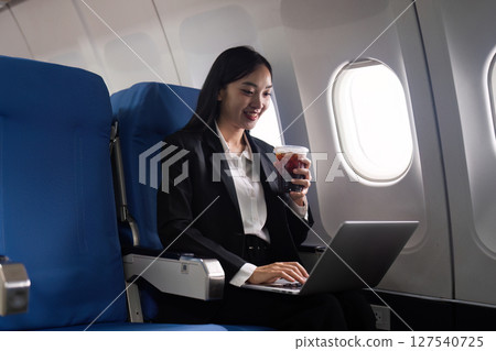 Beautiful Asian businesswoman working with laptop in aeroplane. working, travel, business concept Beautiful Asian businesswoman working with laptop in aeroplane. working, travel, business concept 127540725
