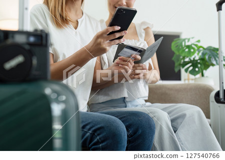 Happy young woman with credit card booking vacation at travel agency or making hotel reservation online 127540766