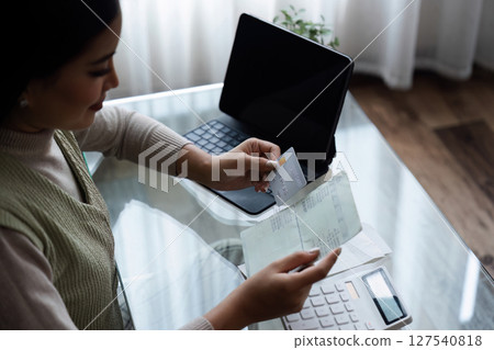 Woman holding credit card and savings account book, saving money, household expenses, monthly bills 127540818