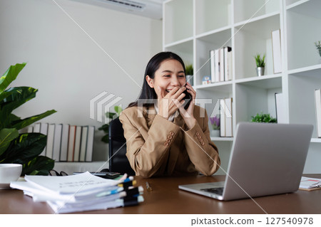 Business woman analysis discussing new project with client on mobile while working with laptop Business woman analysis discussing new project with client on mobile while working with laptop 127540978