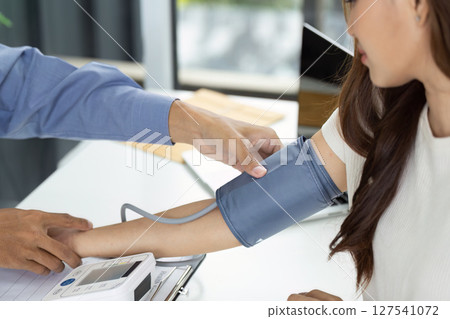 Health Checkup. Medical professional measuring blood pressure of patient in clinic. 127541072