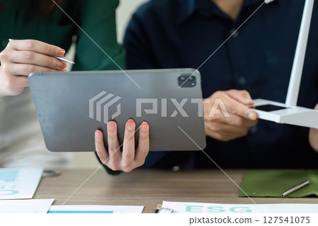 Collaborative ESG Strategy Meeting. Team discussing sustainability using digital tablet. Collaborative ESG Strategy Meeting. Team discussing sustainability using digital tablet. 127541075