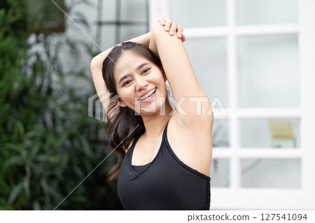 Wellness and Fitness. Young woman stretching and smiling outdoors, promoting healthy lifestyle and self-care. 127541094