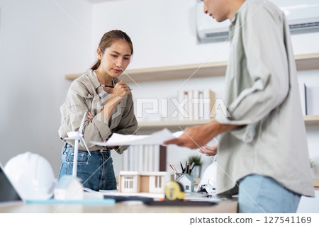 Architectural Team Discussion. Architect evaluating plans with a colleague in an office. Architectural Team Discussion. Architect evaluating plans with a colleague in an office. 127541169