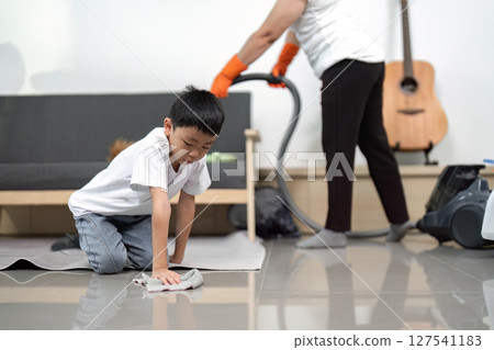 Cleaning and Family Bonding. A young boy helps with household cleaning while enjoying time with his mother. 127541183